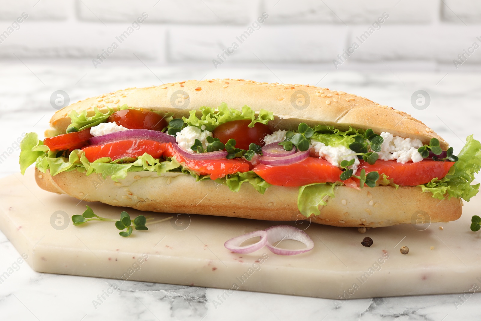 Photo of Delicious baguette with salmon on white marble table, closeup