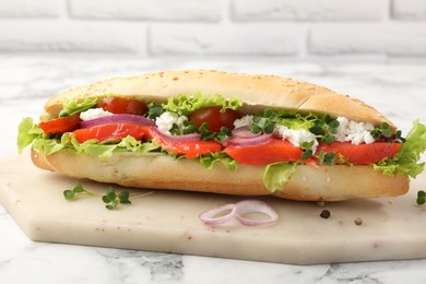 Photo of Delicious baguette with salmon on white marble table, closeup