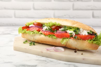 Photo of Delicious baguette with salmon on white marble table, closeup