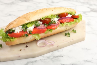 Photo of Delicious baguette with salmon on white marble table, closeup