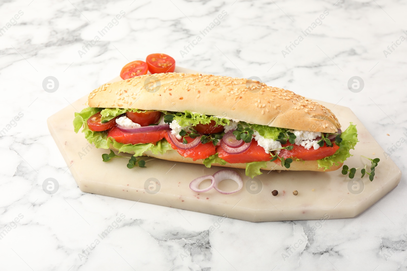 Photo of Delicious baguette with salmon on white marble table