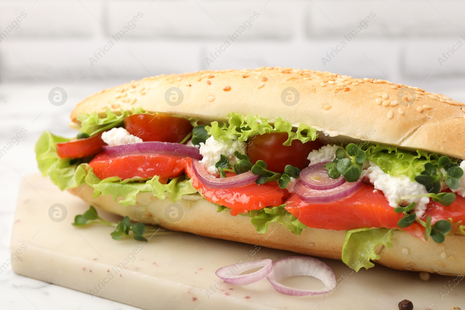 Photo of Delicious baguette with salmon on white table, closeup