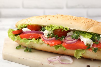 Photo of Delicious baguette with salmon on white table, closeup