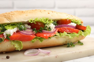 Photo of Delicious baguette with salmon on white table, closeup