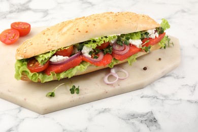 Photo of Delicious baguette with salmon on white marble table, closeup