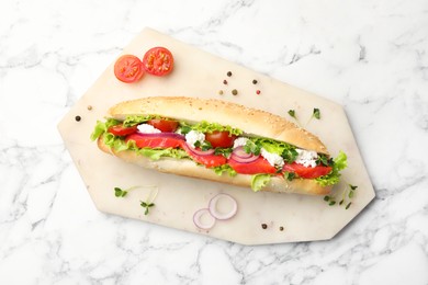 Photo of Delicious baguette with salmon on white marble table, top view