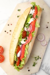 Photo of Delicious baguette with salmon on white marble table, top view