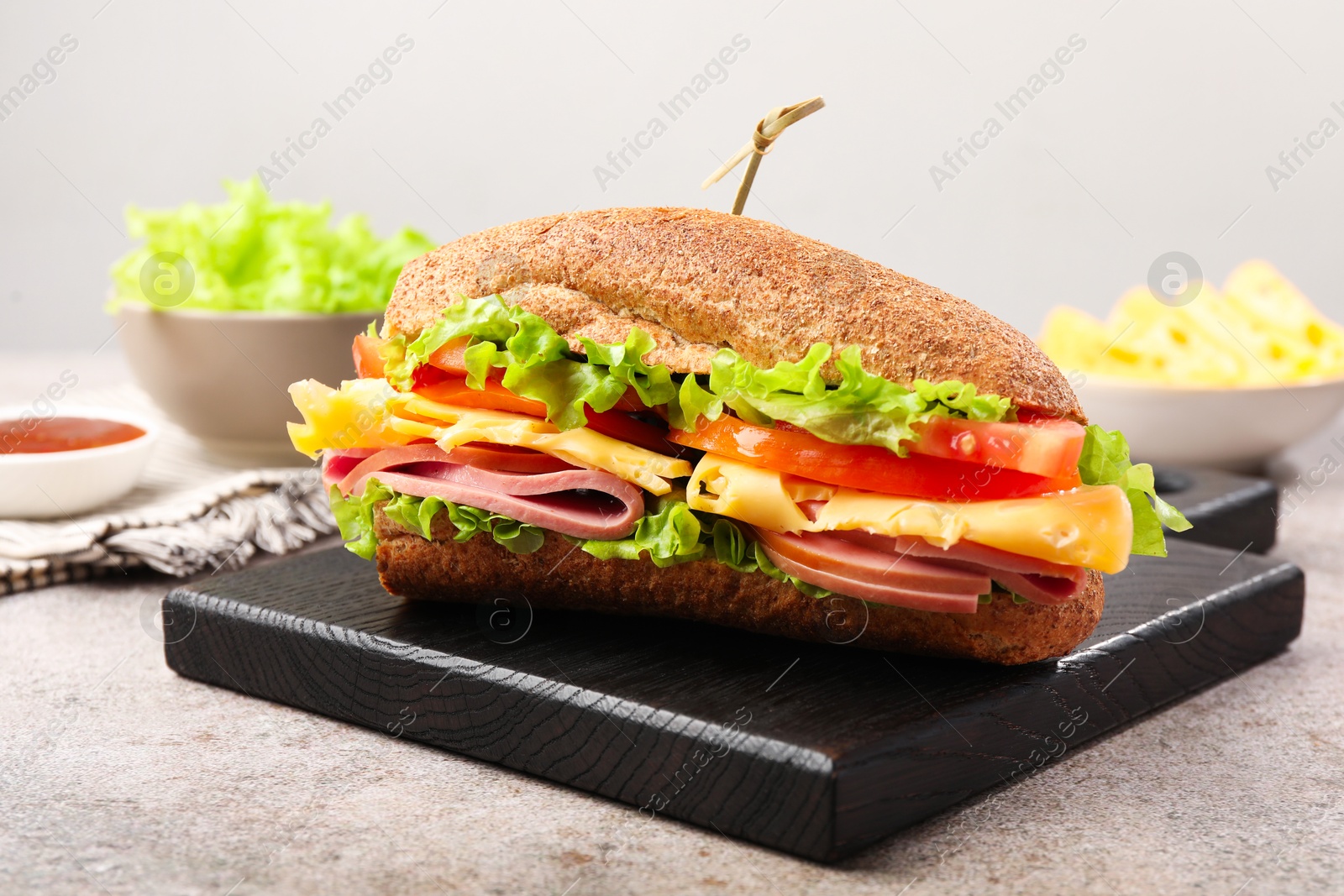 Photo of Delicious baguette sandwich with ham on grey table