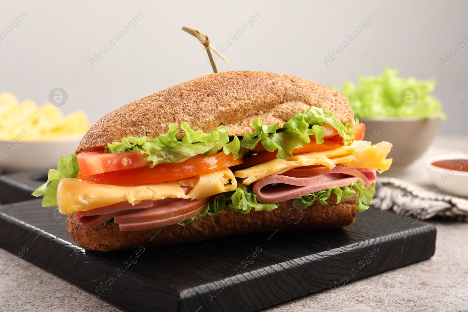 Photo of Delicious baguette sandwich with ham on grey table, closeup