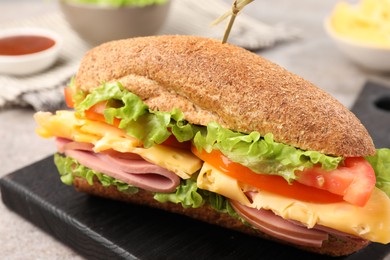 Photo of Delicious baguette sandwich with ham on grey table, closeup