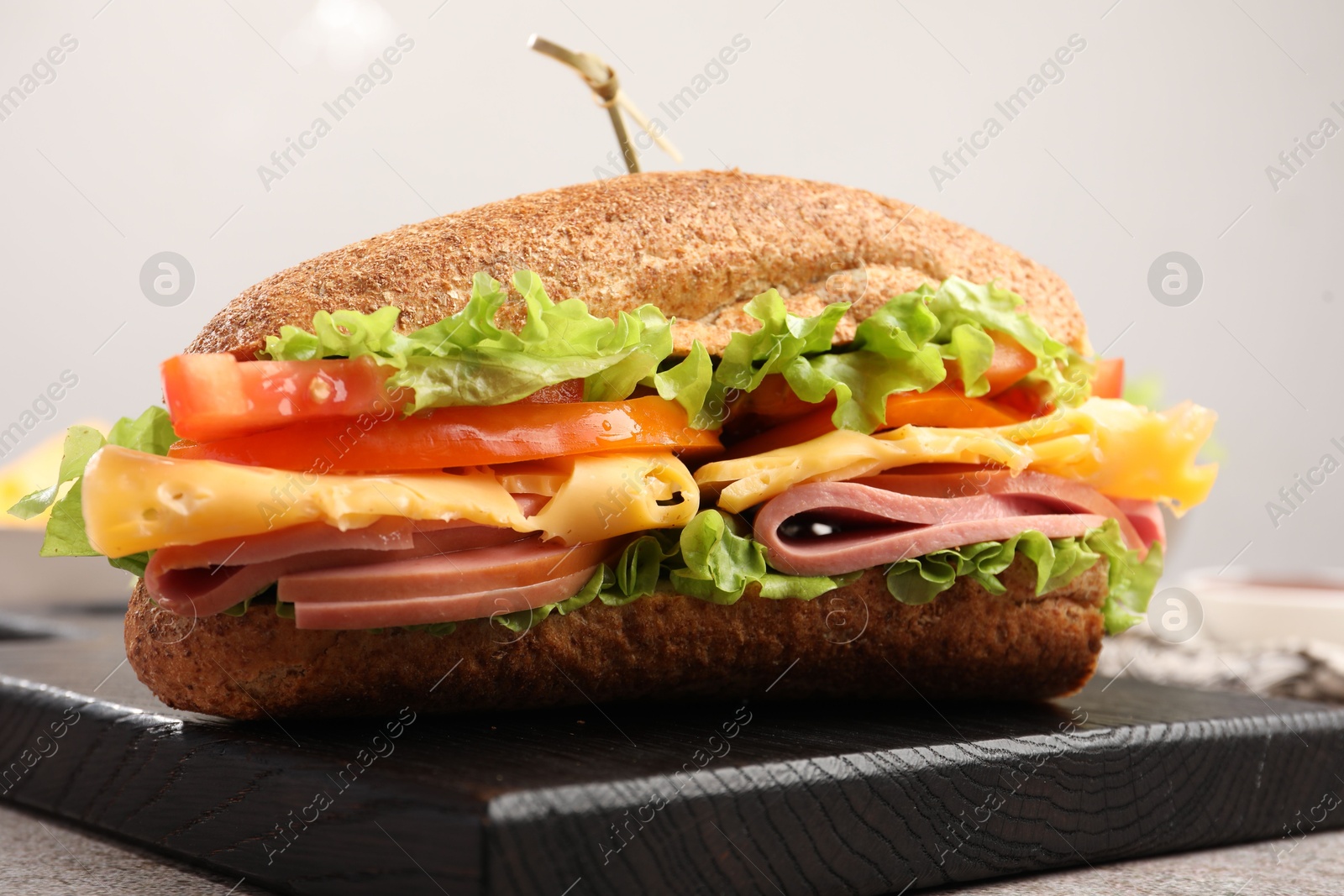 Photo of Delicious baguette sandwich with ham on grey table, closeup