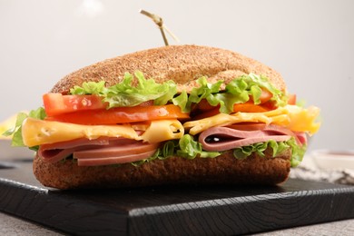 Photo of Delicious baguette sandwich with ham on grey table, closeup