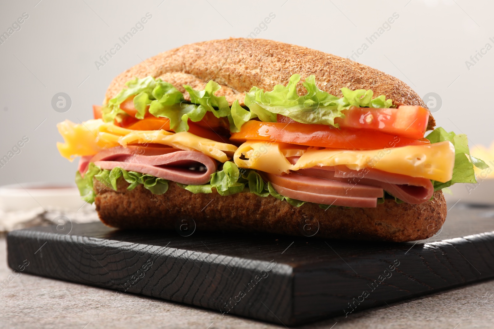 Photo of Delicious baguette sandwich with ham on grey table, closeup