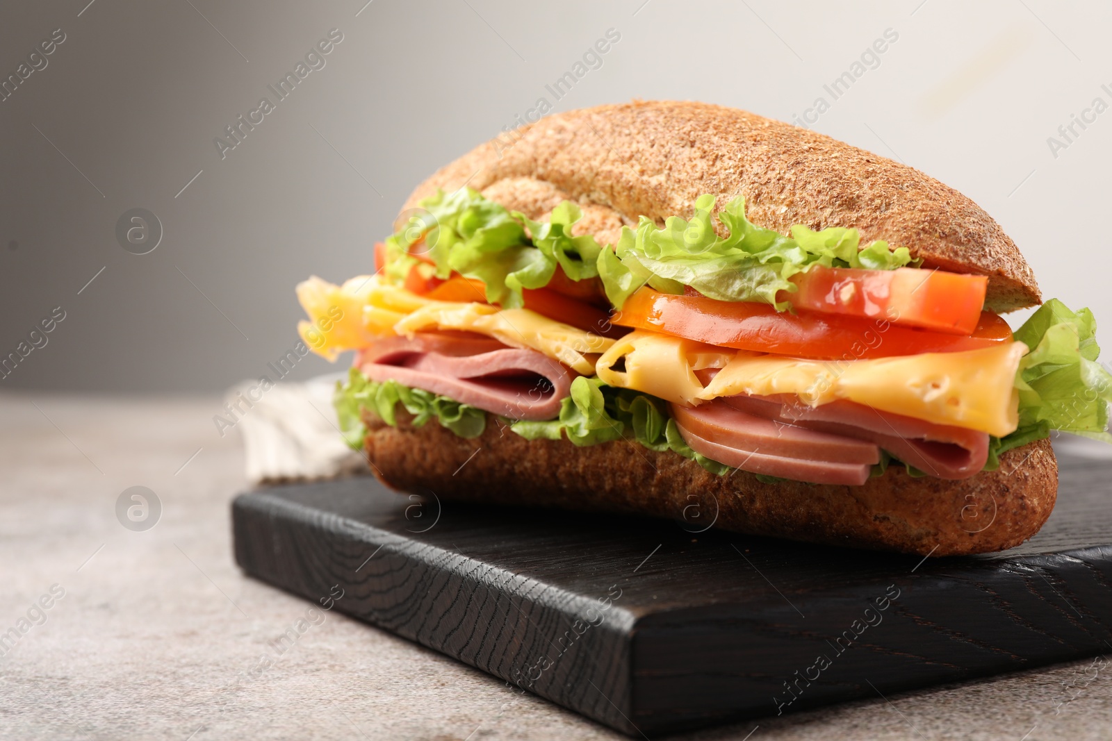 Photo of Delicious baguette sandwich with ham on grey table, closeup