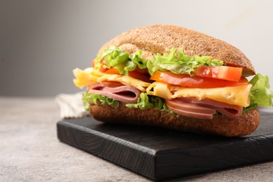 Photo of Delicious baguette sandwich with ham on grey table, closeup