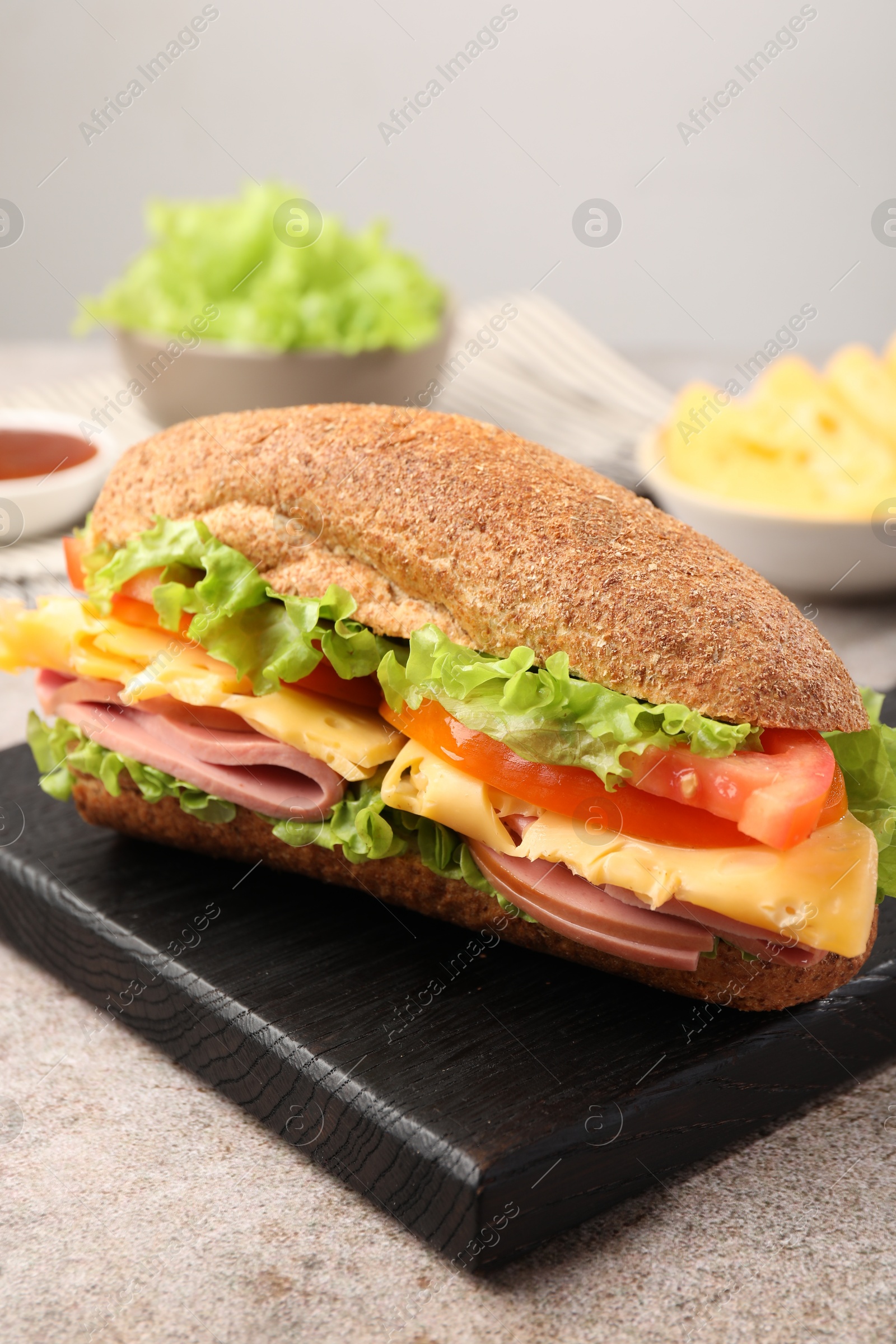 Photo of Delicious baguette sandwich with ham on grey table, closeup