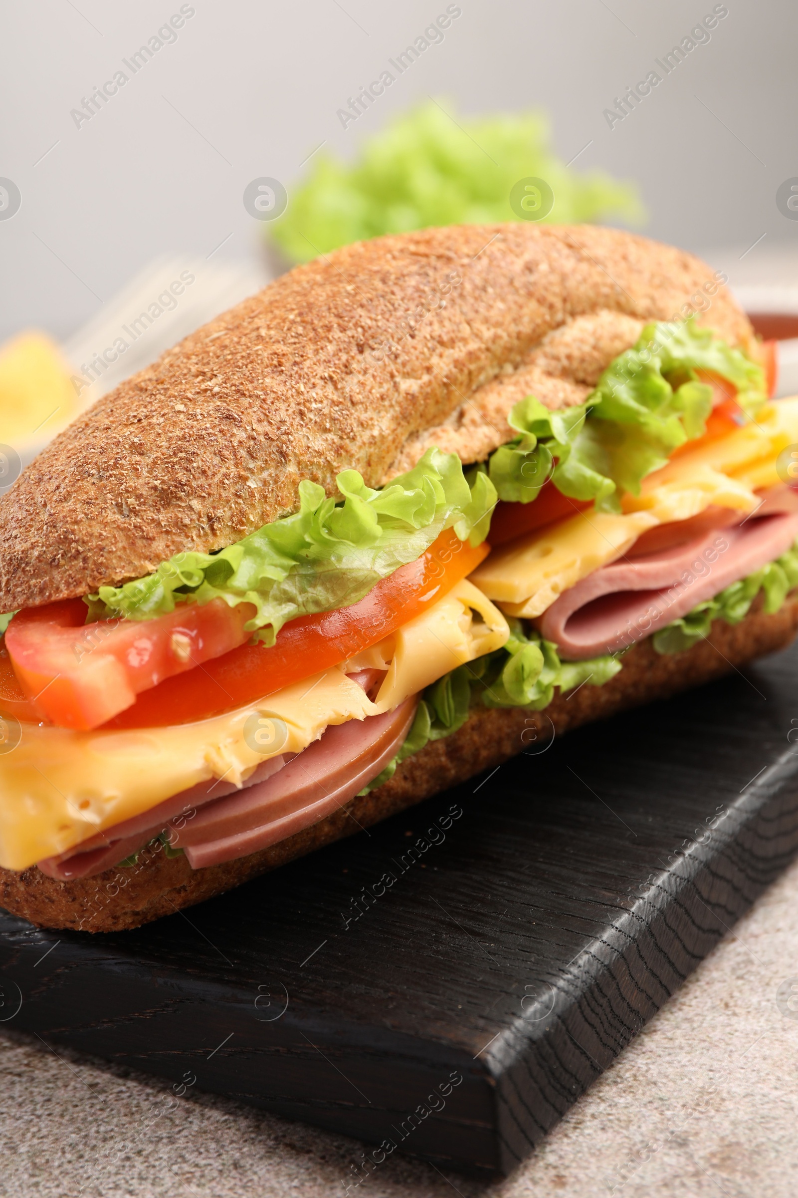 Photo of Delicious baguette sandwich with ham on grey table, closeup