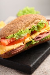 Photo of Delicious baguette sandwich with ham on grey table, closeup