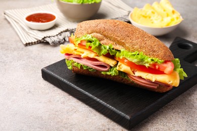 Photo of Delicious baguette sandwich with ham and ingredients on grey table