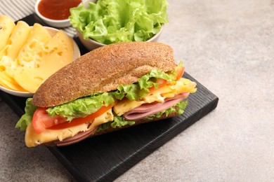 Photo of Delicious baguette sandwich with ham and ingredients on grey table