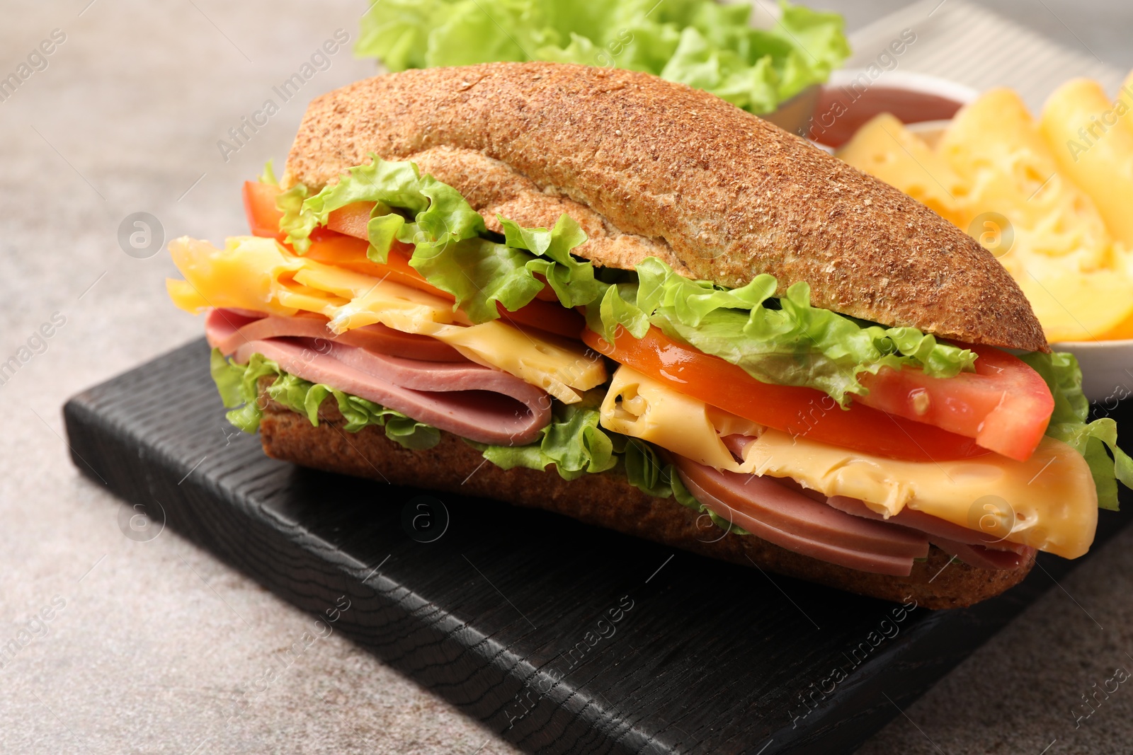 Photo of Delicious baguette sandwich with ham on grey table, closeup