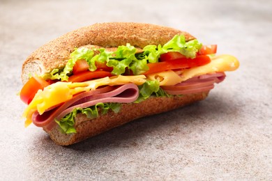 Photo of Delicious baguette sandwich with ham on grey table, closeup