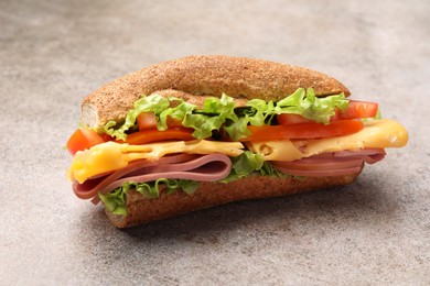 Photo of Delicious baguette sandwich with ham on grey table, closeup