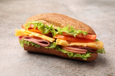 Photo of Delicious baguette sandwich with ham on grey table, closeup