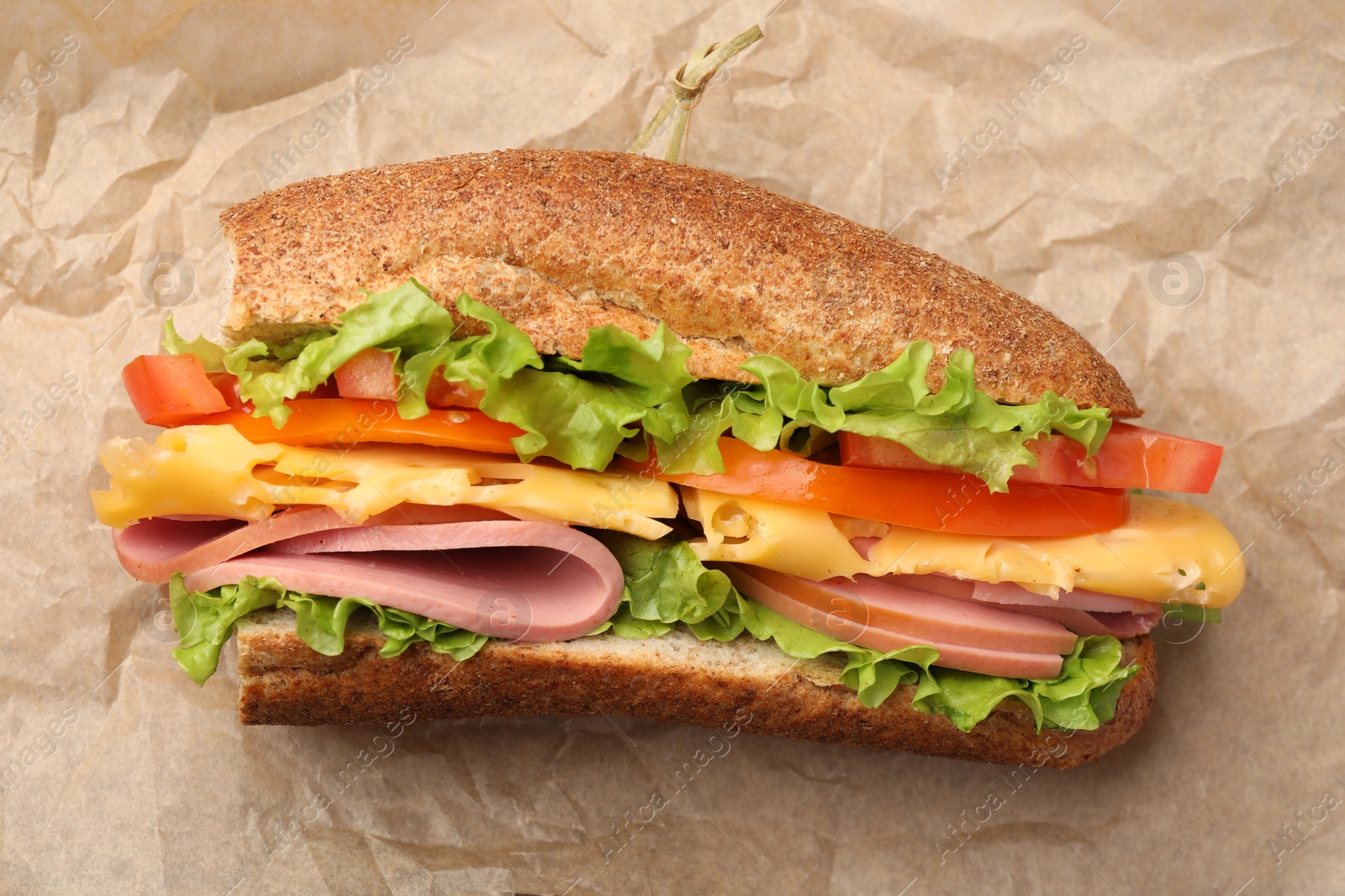 Photo of Delicious baguette sandwich on parchment paper, top view