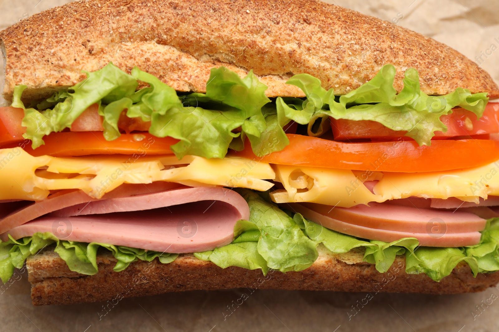 Photo of Delicious baguette sandwich on parchment paper, top view