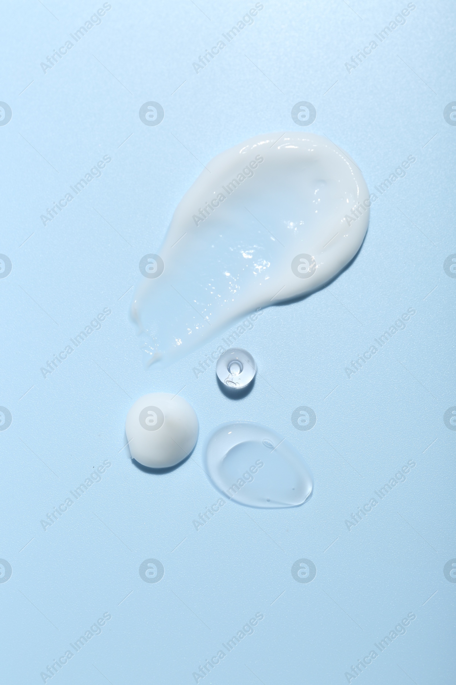 Photo of Cream and gel samples on light blue background, top view