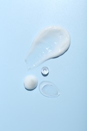 Photo of Cream and gel samples on light blue background, top view