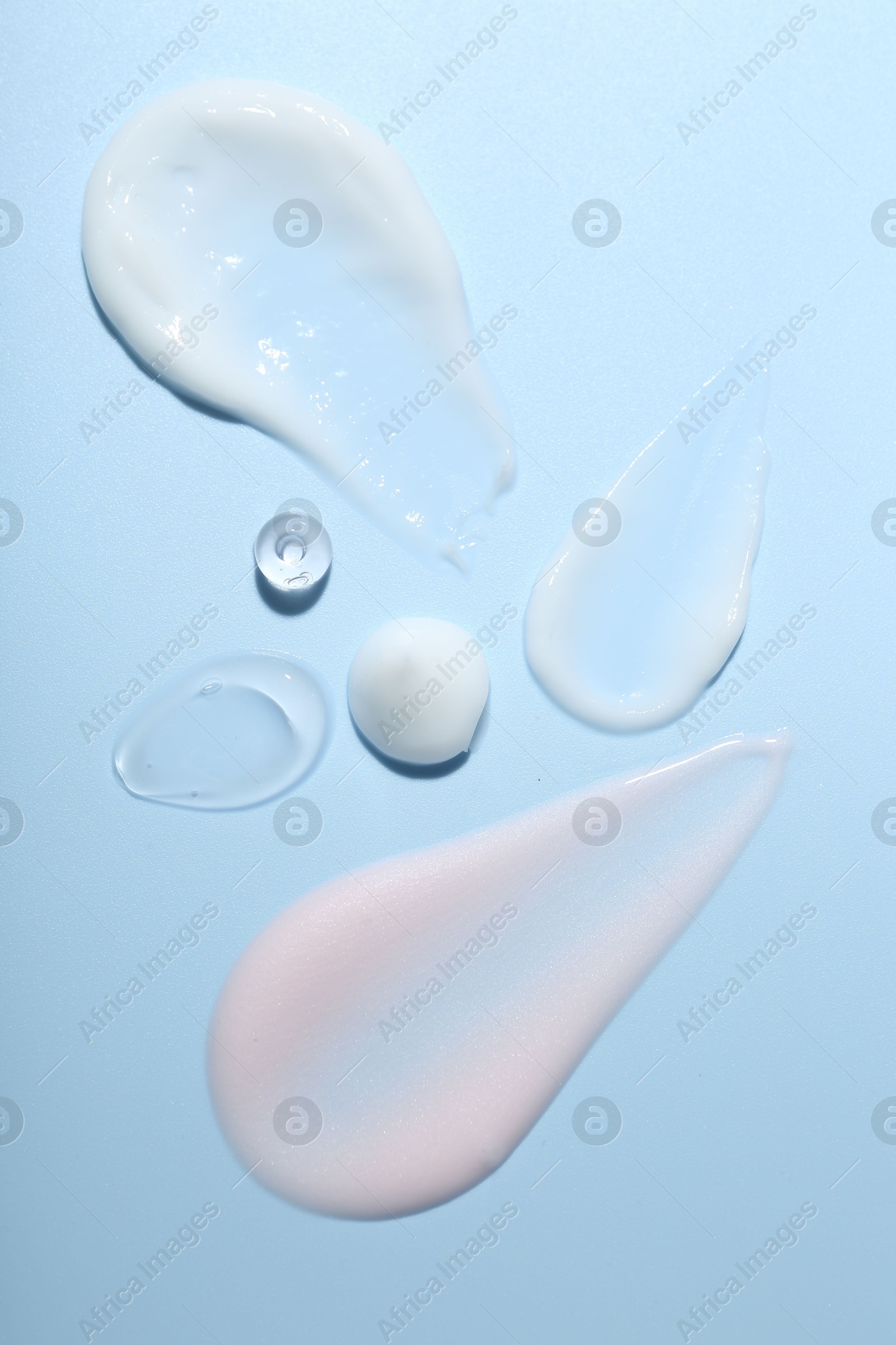 Photo of Cream and gel samples on light blue background, top view