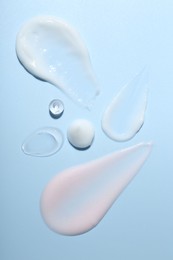 Photo of Cream and gel samples on light blue background, top view