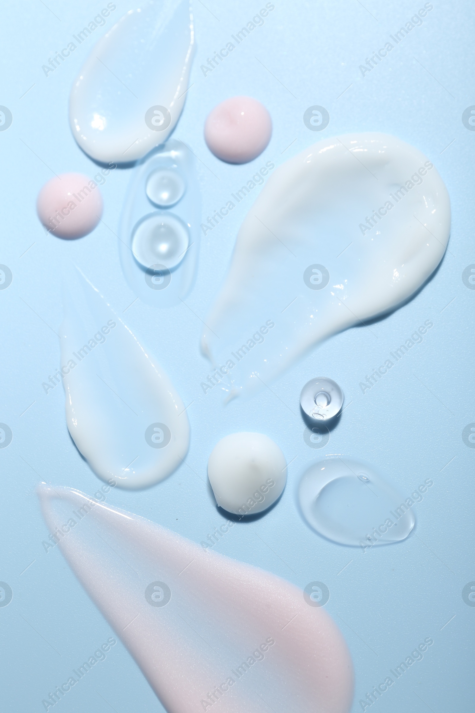 Photo of Cream and gel samples on light blue background, top view