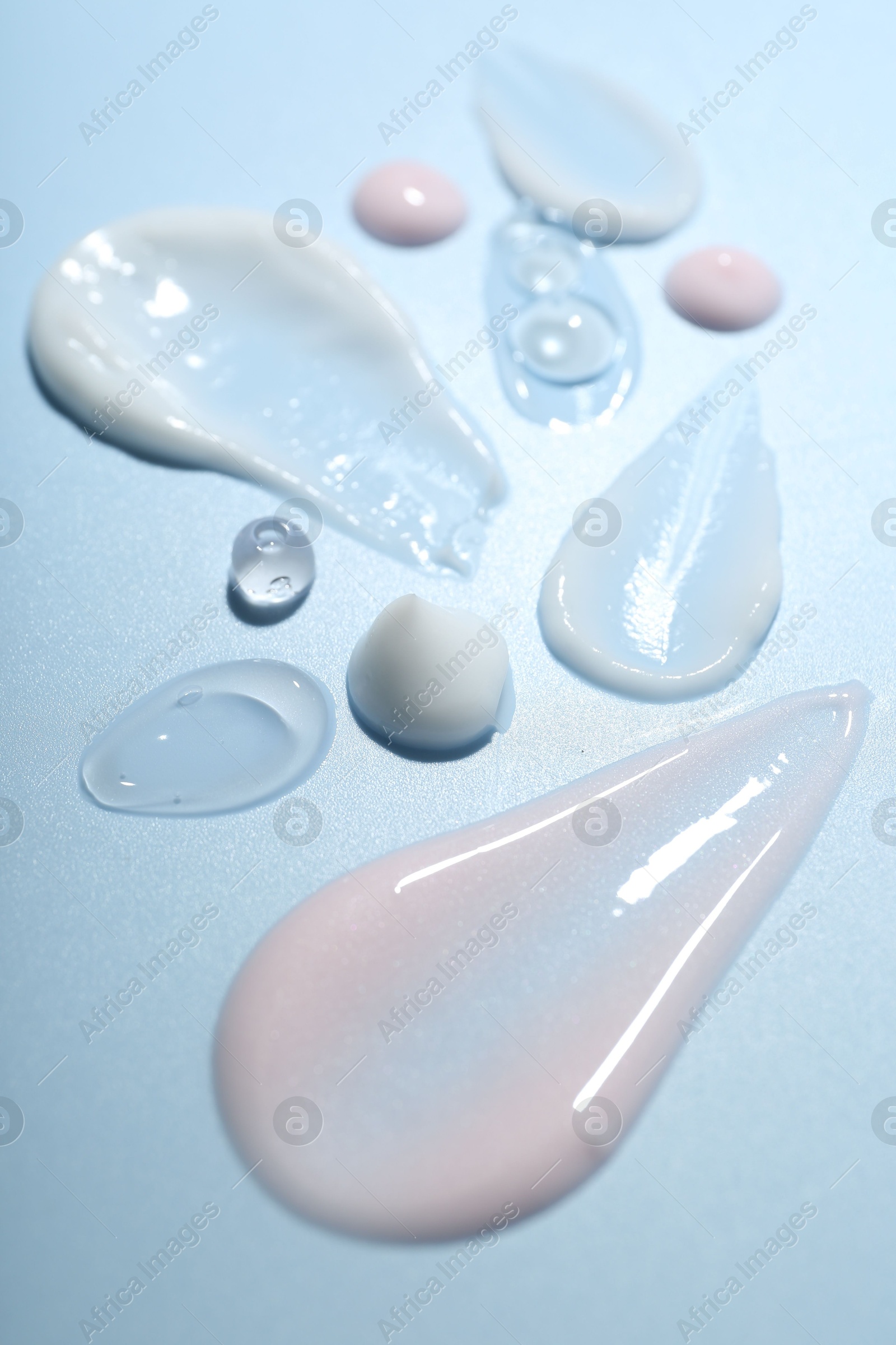 Photo of Cream and gel samples on light blue background, closeup