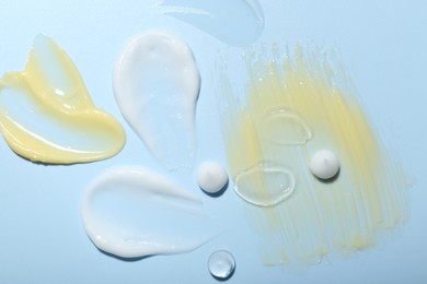 Photo of Cream and gel samples on light blue background, top view