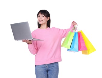 Photo of Internet shopping. Smiling woman with laptop and colorful bags on white background