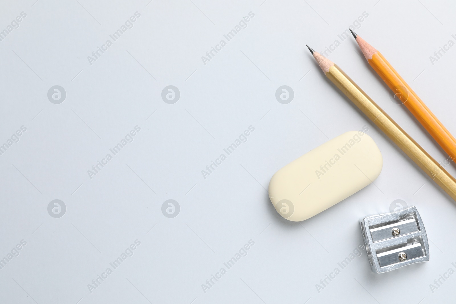 Photo of Eraser, pencils and sharpener on light background, top view. Space for text