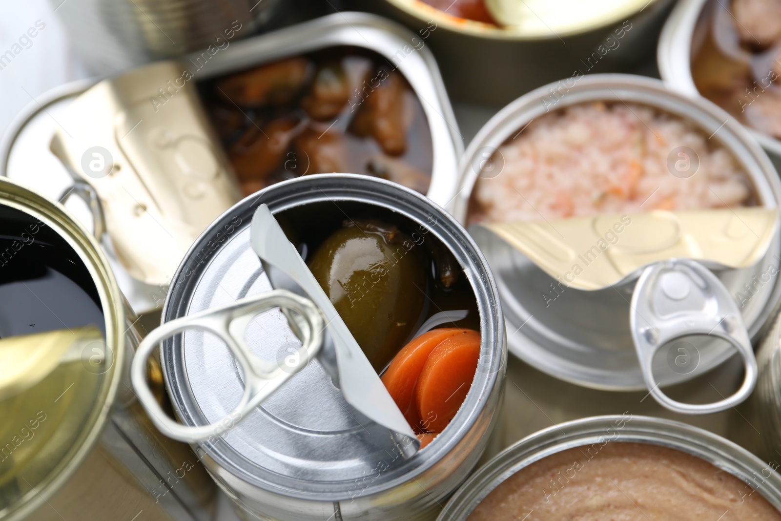 Photo of Open tin cans with different preserved products on table, above view