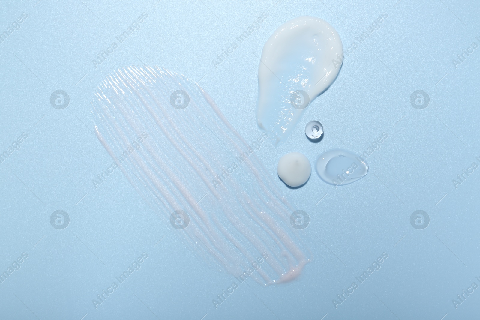 Photo of Cream and gel samples on light blue background, top view