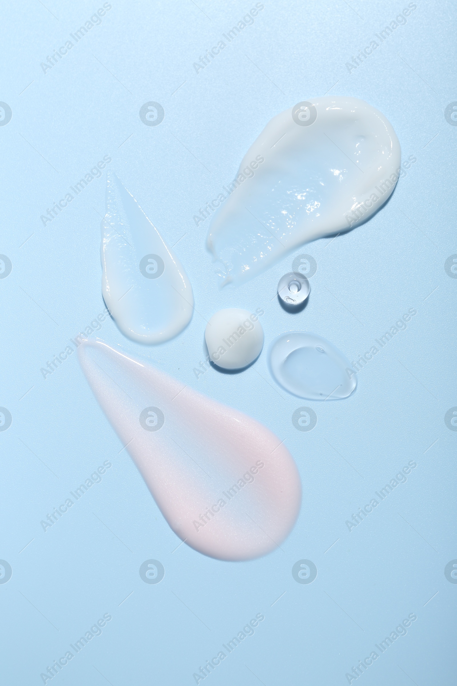 Photo of Cream and gel samples on light blue background, top view