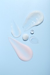 Photo of Cream and gel samples on light blue background, top view