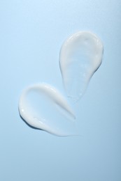 Photo of Cream samples on light blue background, top view