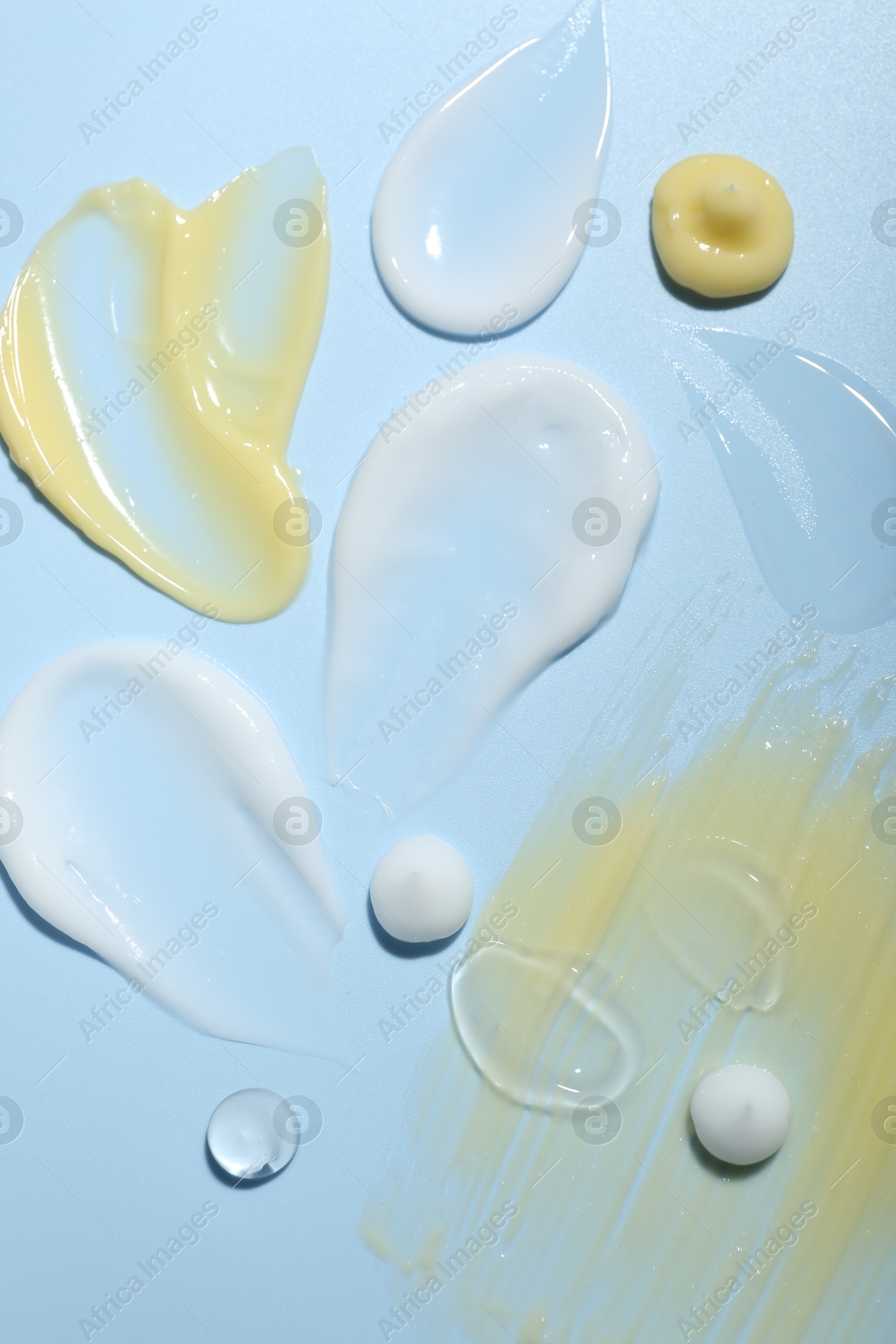 Photo of Cream and gel samples on light blue background, top view