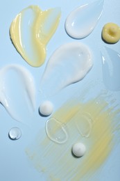 Photo of Cream and gel samples on light blue background, top view