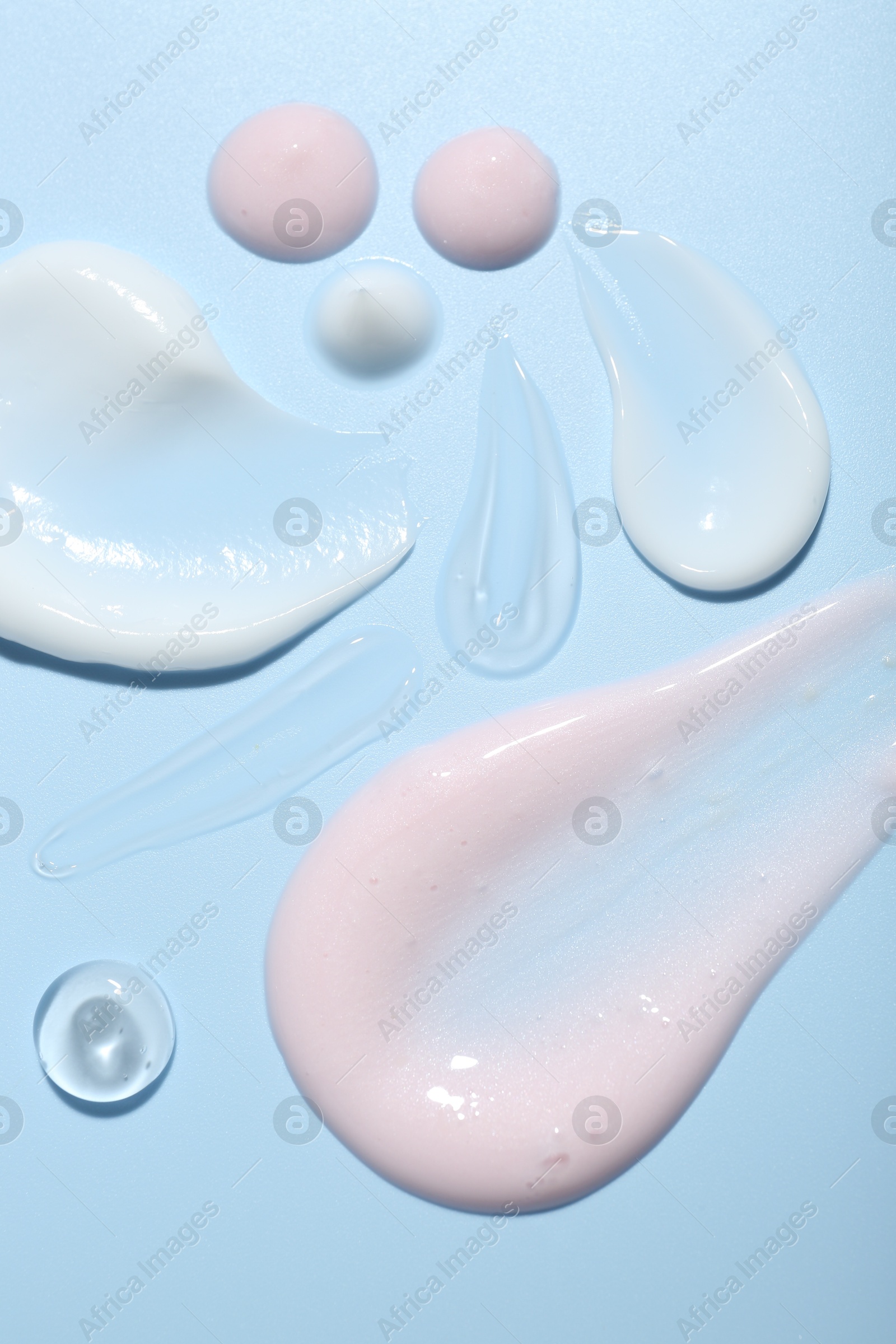 Photo of Cream and gel samples on light blue background, top view