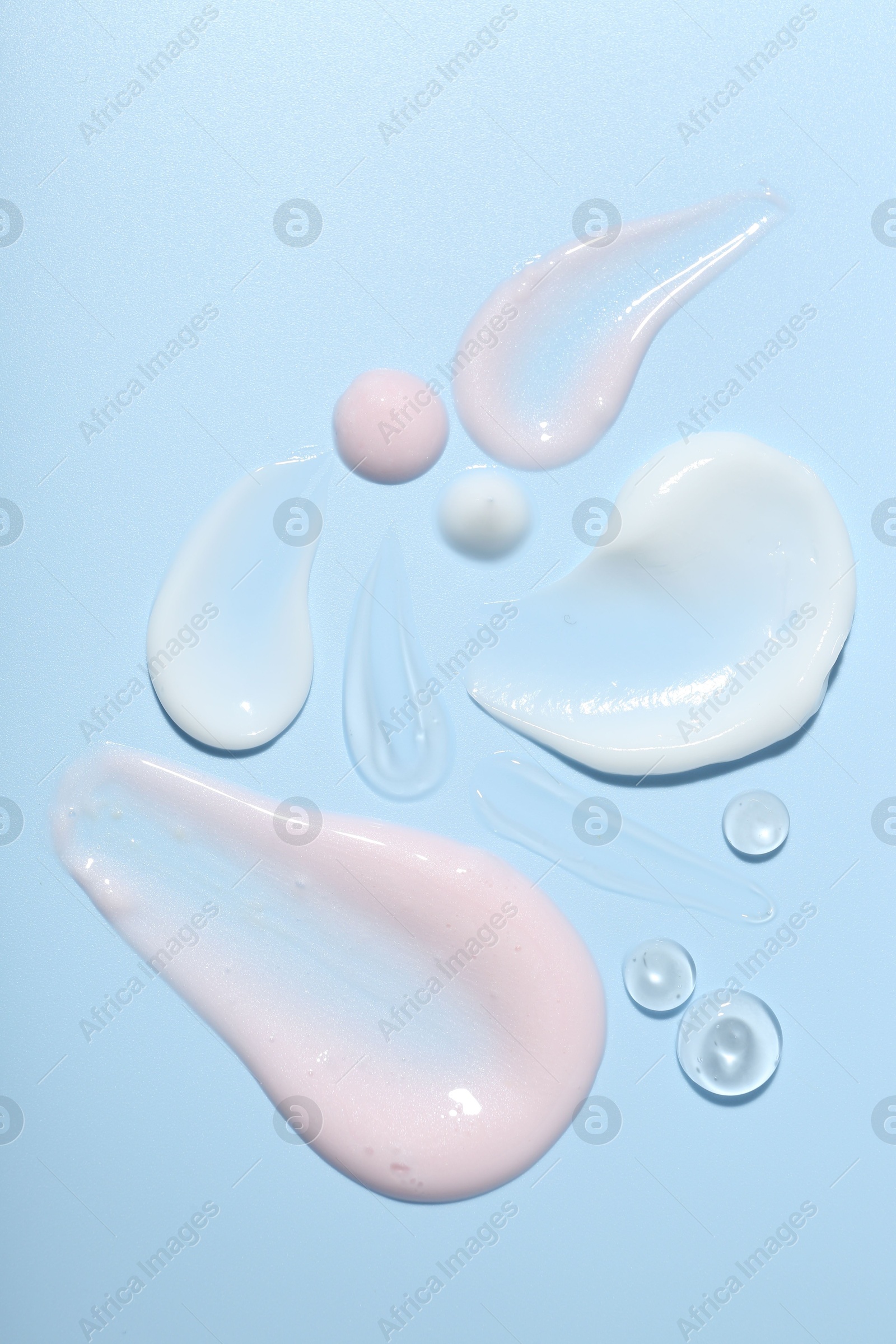 Photo of Cream and gel samples on light blue background, top view