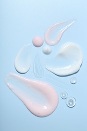 Photo of Cream and gel samples on light blue background, top view