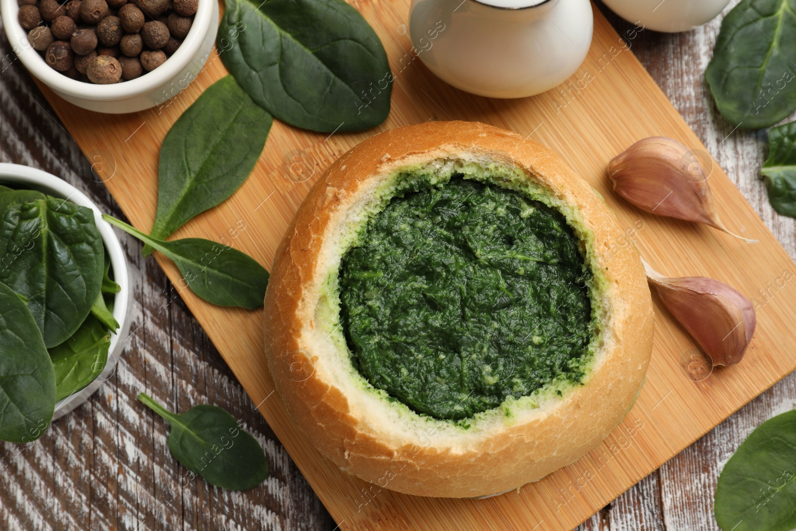 Photo of Delicious spinach sauce in bread bowl on wooden table, flat lay